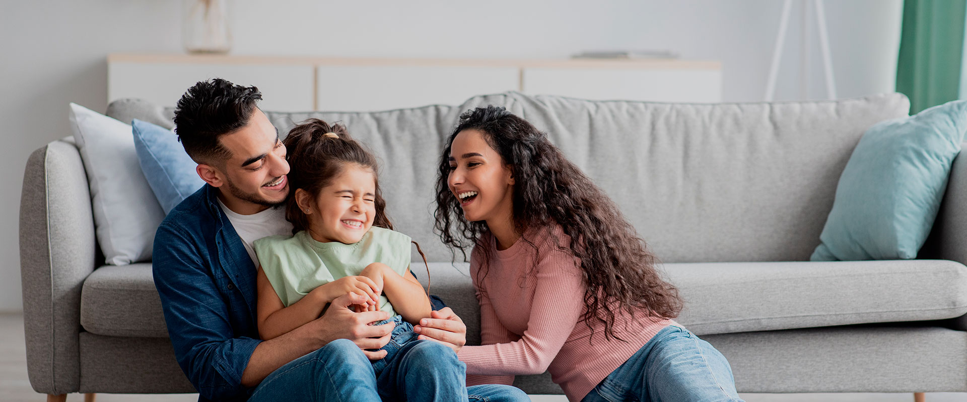 homem, mulher e criança rindo no sofa